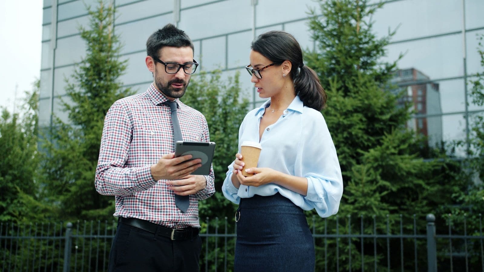 Deux commerciaux terrain consultent l'activité client sur une tablette devant un bureau
